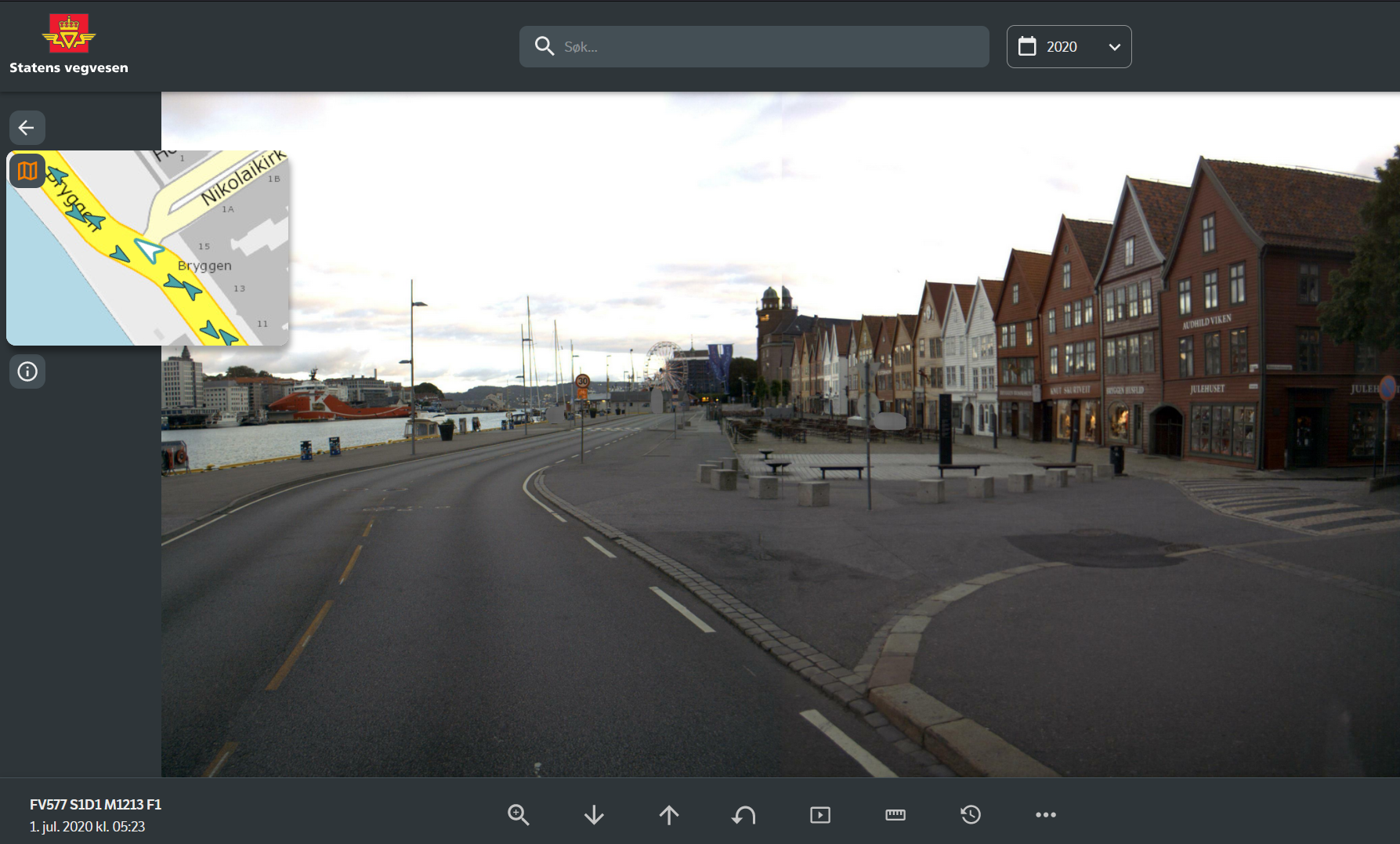 Statens vegvesen logo, søkefelt, nedtrekksmeny med val av år, kartvindu med utsnitt av vegen med piler som viser kjøreretning, foto av veg og hus på same stad som kartutsnittet.